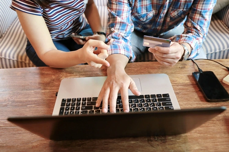 Shot of a man and woman looking at a laptop screen holding a credit card