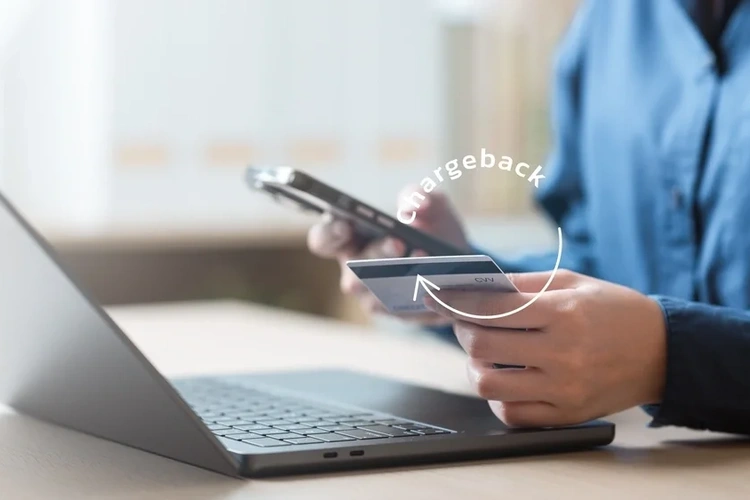 Close up of a man at his laptop holding a credit card in one hand and a mobile phone in the other