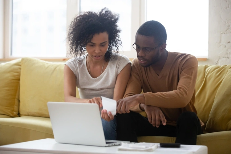 A man and woman looking at a bill with a laptop