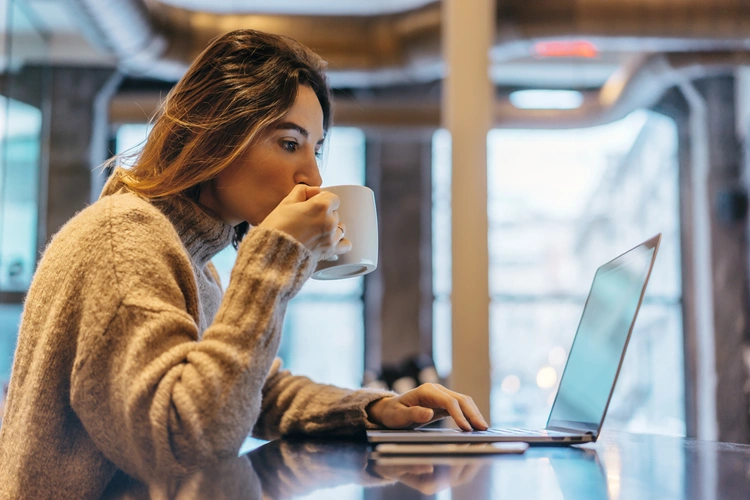 young woman on laptop drinking coffee