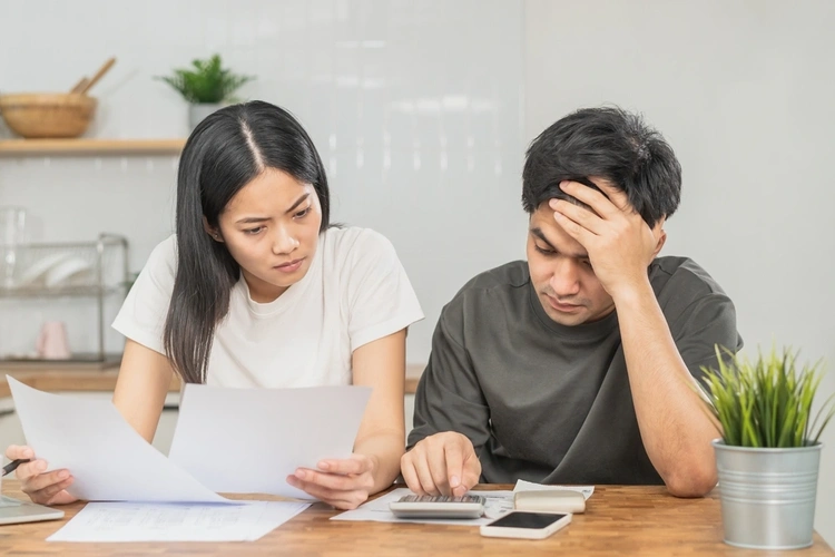 A man and woman looking at bills and using a calculator