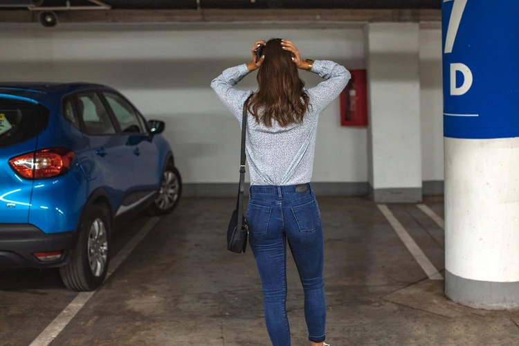 Woman stood with hands on her head looking at empty car space