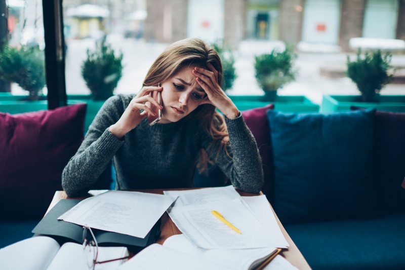 Lady on phone looking distressed whilst going through paperwork