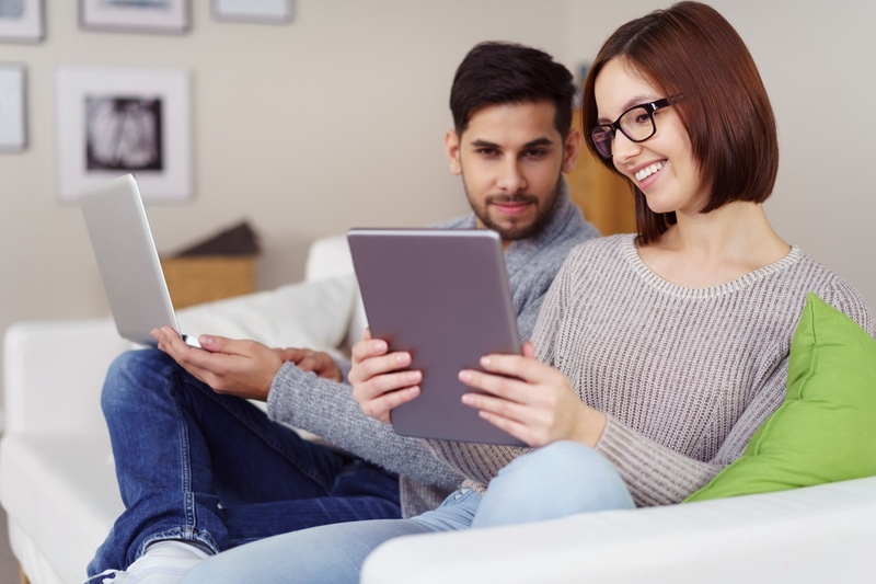 Couple on sofa looking at loans on a laptop and tablet
