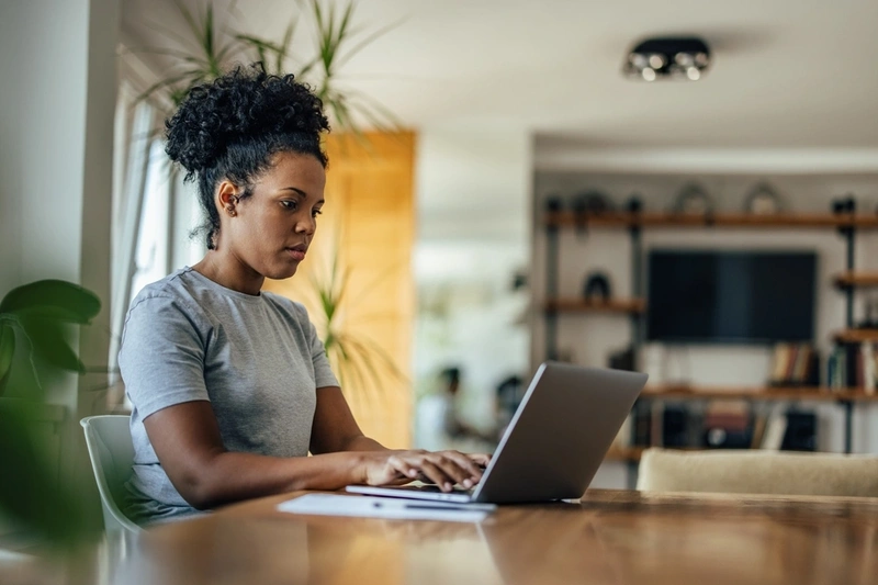 Woman on her laptop at the table looking for credit card deals.