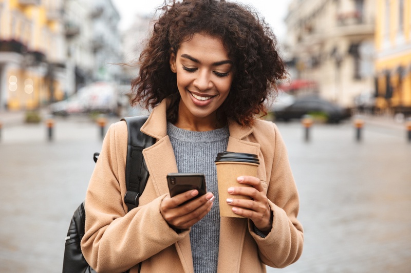 Woman checking her credit score on her phone while holding a coffee cup