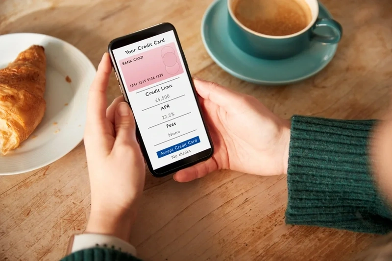 Image of a woman holding a mobile which shows credit card details