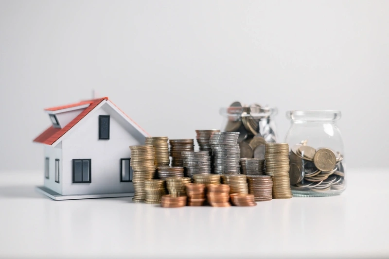 Toy house with money stacked next to it