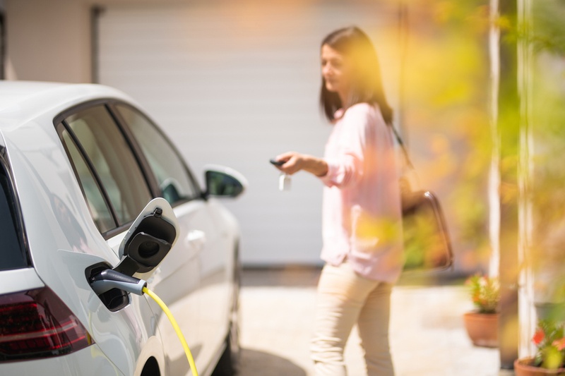 Woman standing next to her electric car whilst it charges