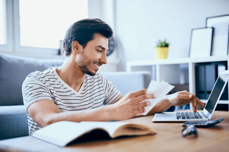 Man going through his bills and typing on a laptop