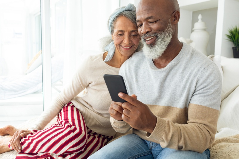 An older couple sitting on sofa looking at possible loans on their phone
