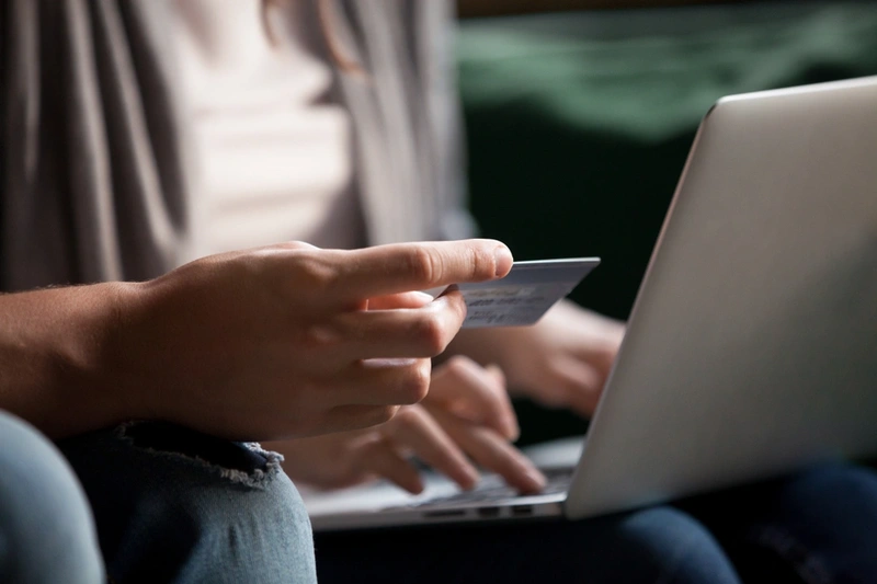 Close up of someone holding a credit card whilst on the laptop