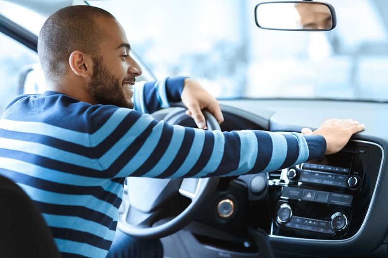 Man sat in car, touching the dashboard.