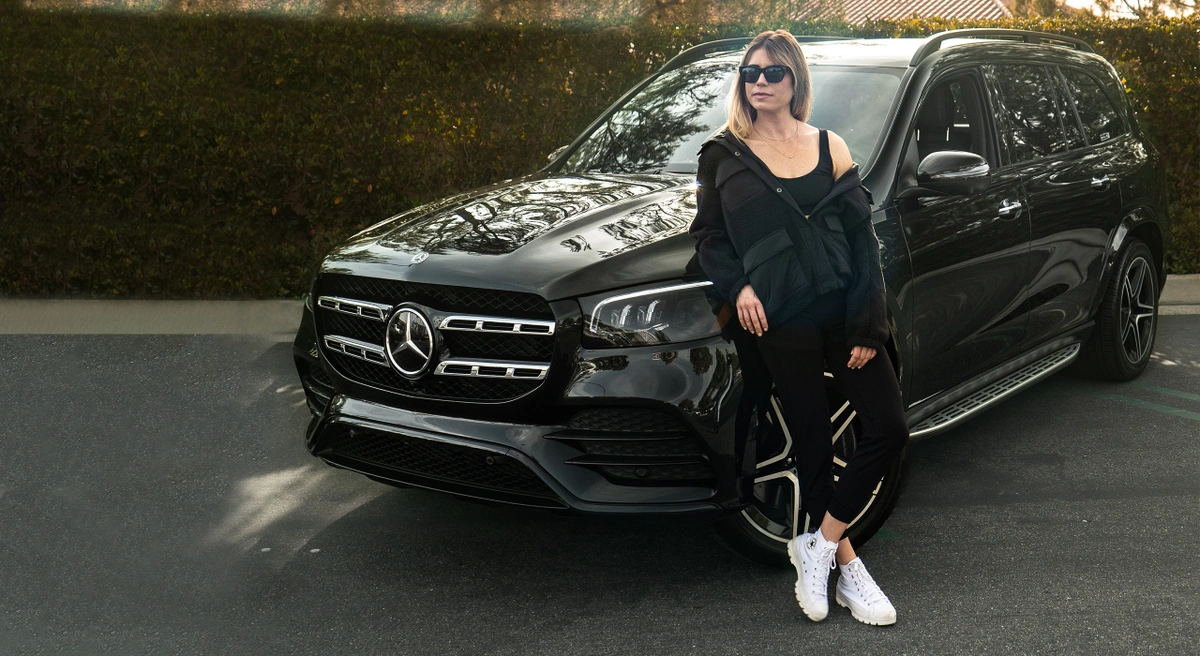 Hosting during the Recession - female host in front of black Mercedes GLS