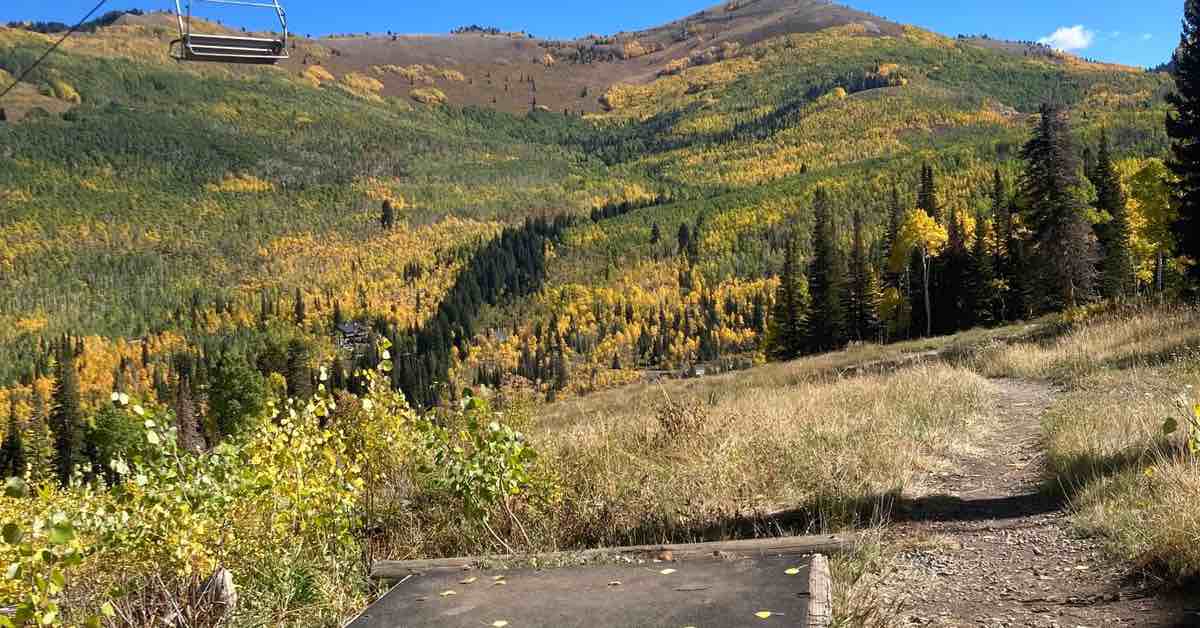 A rubber disc golf tee pad an a view of mountains with trees tinged in fall yellow