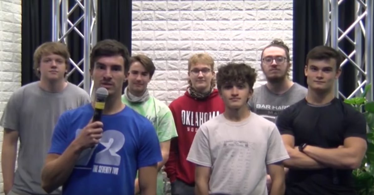 A group of young boys, on with a microphone, look into a camera