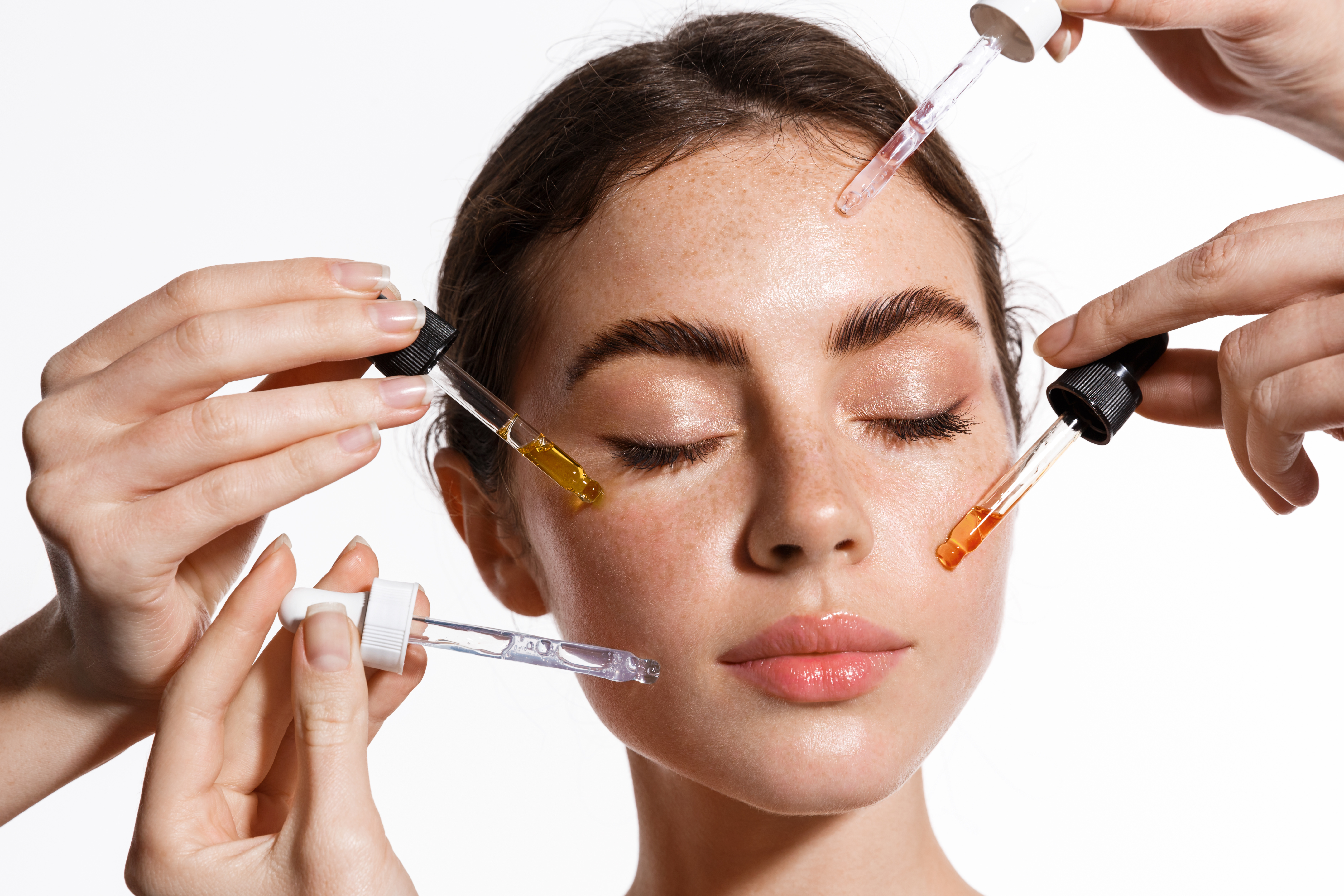 Many medicine droppers of serums putting antiaging serums skin care products on the face