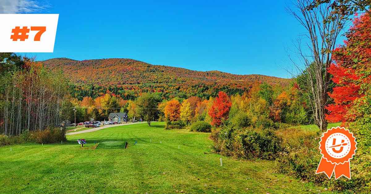 A view of a well-mowed fairway and a rolling mountain landscape in fall colors