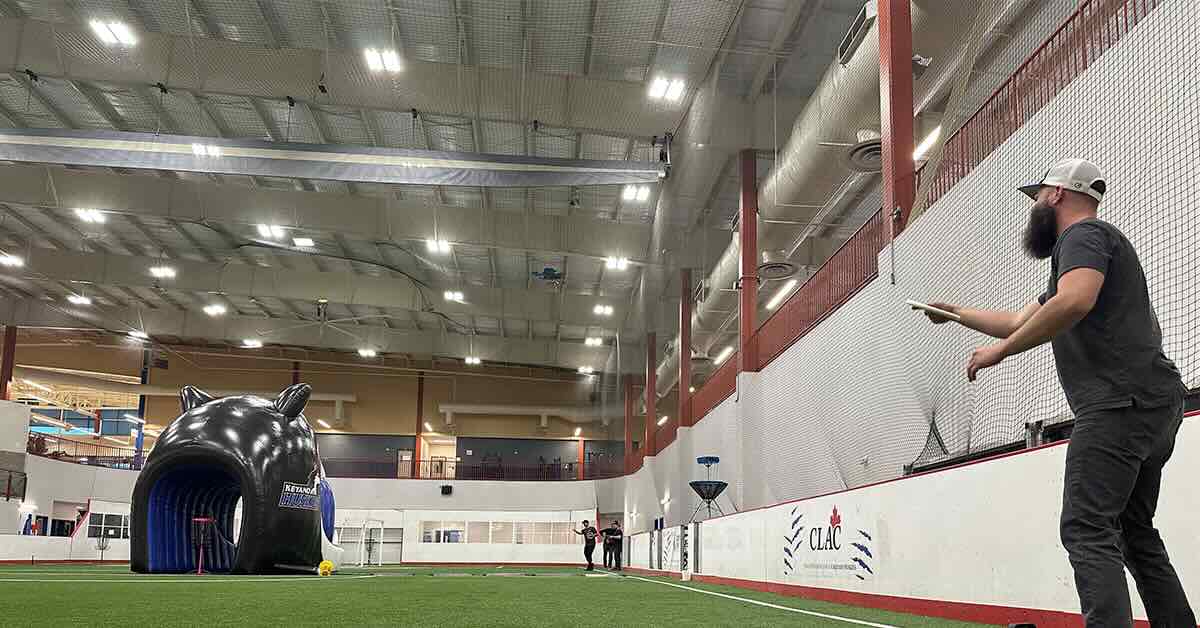 A man lines up a putt to a basket and disc golf basket stands inside an inflatable Husky head