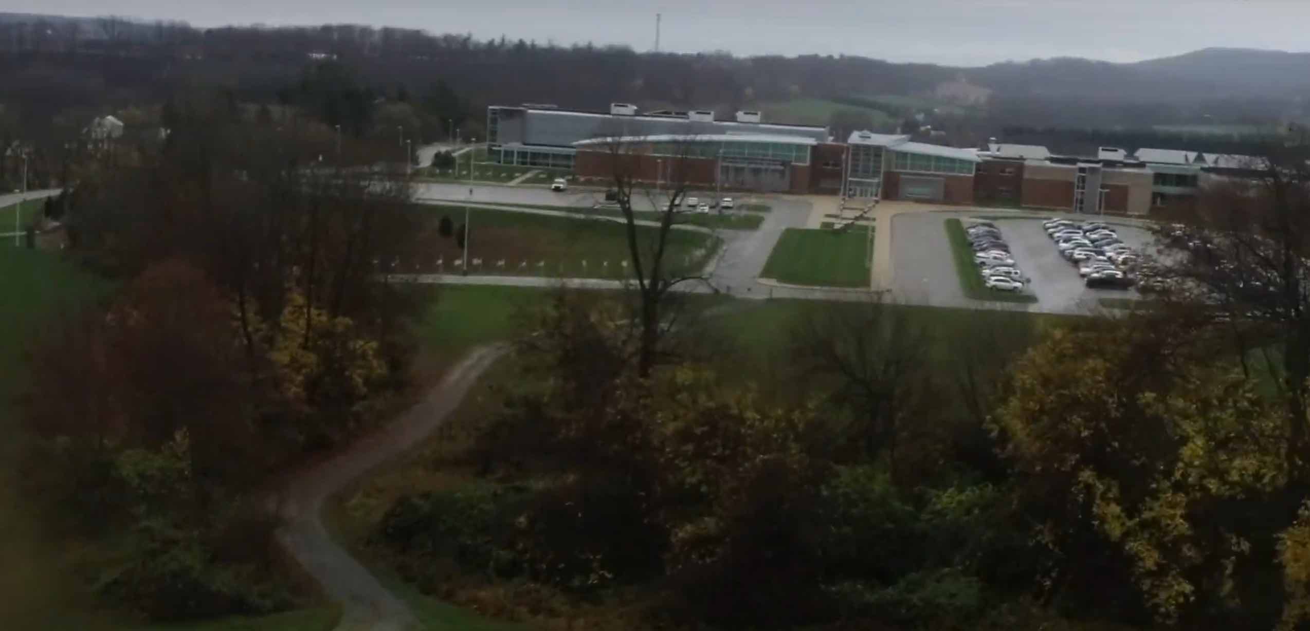 Bird's-eye view of a small green space in front of a school and parking lot