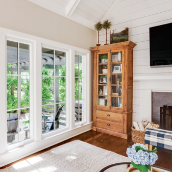 Living room with wood bookshelf and white fiberglass casement windows from Infinity from Marvin
