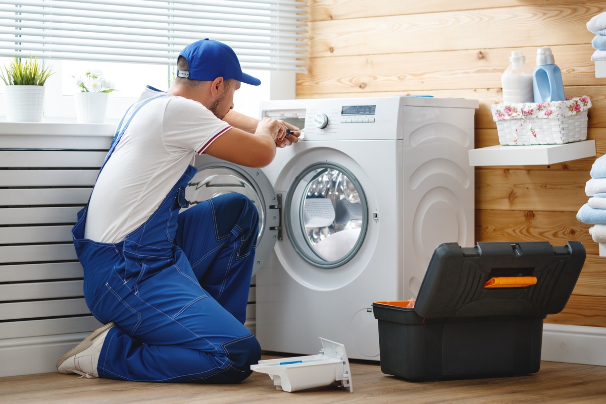 Appliance repair technician working on a washing machine.