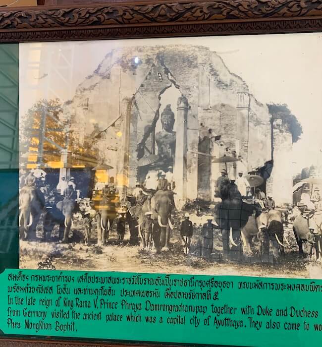 old photo with people riding in elephants in front of a big buddha