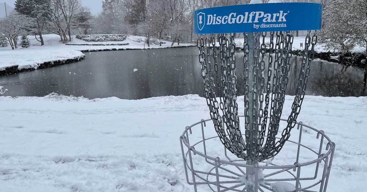 A disc golf basket with a blue band in snowy weather
