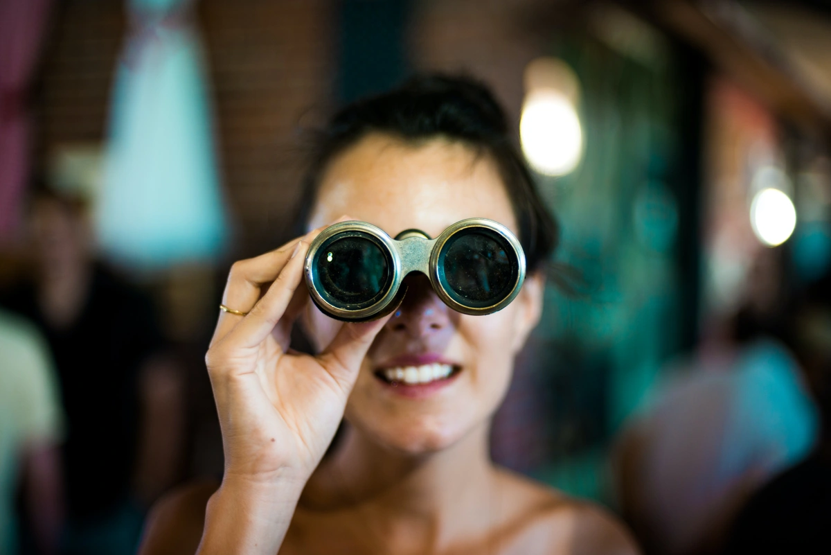 Woman looking through binoculars. It’s important to learn from your competitors.