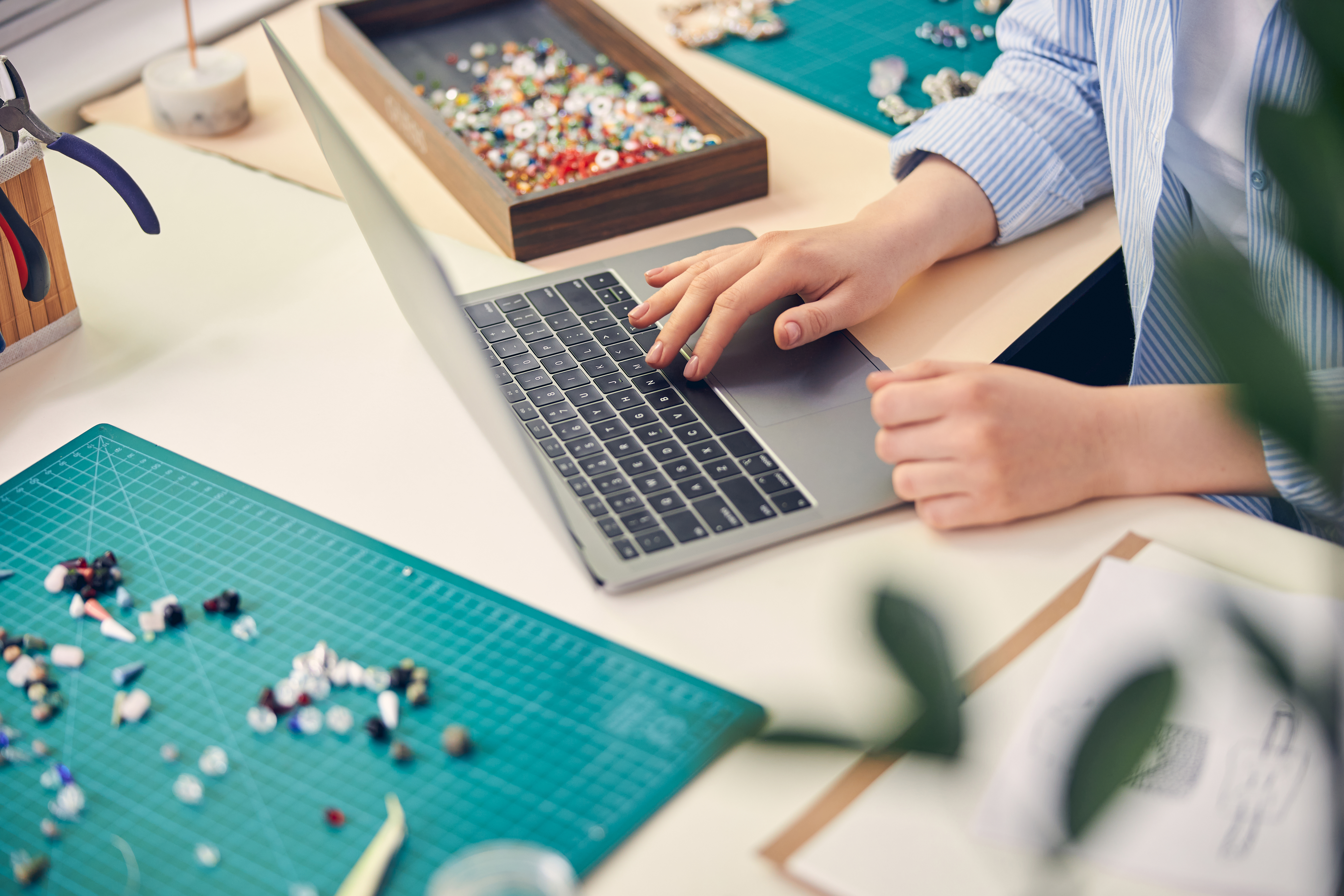 woman using laptop surrounded by beads 