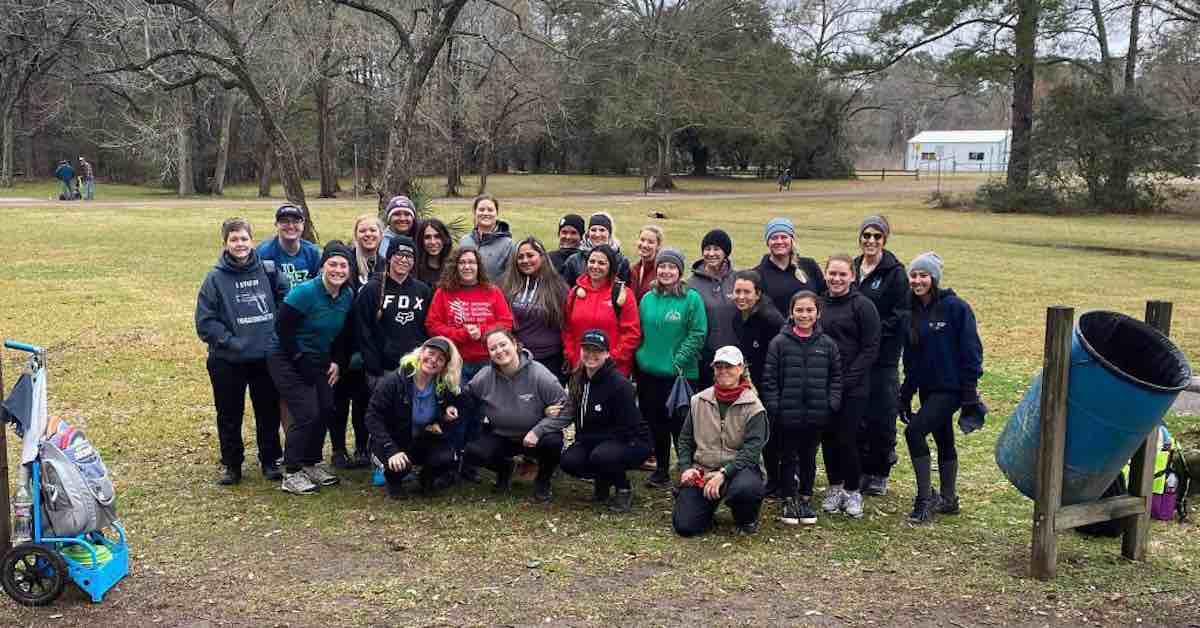 A group of disc golfing women pose for a photo on a dreary day.