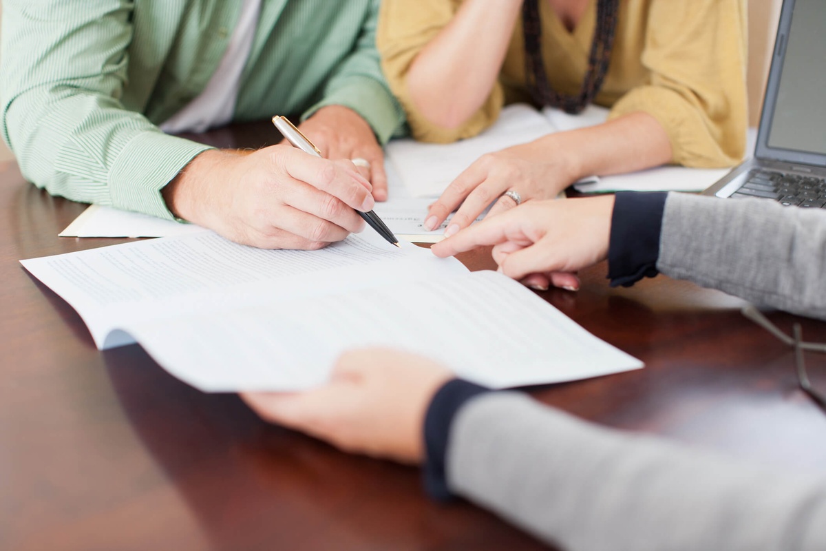 Someone signing a document in front of a witness