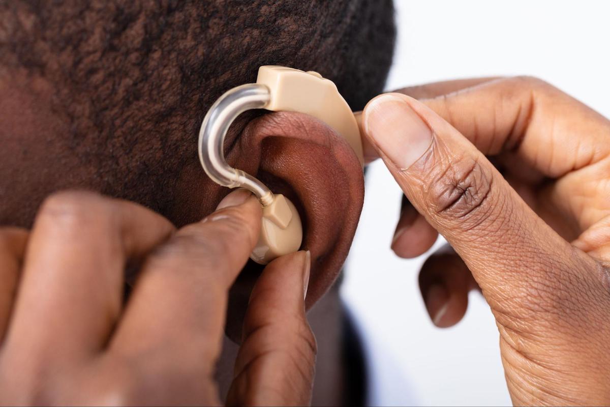 Person putting a hearing aid on another person's ear