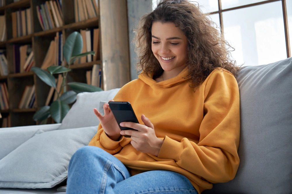 Woman smiling whilst looking at her mobile