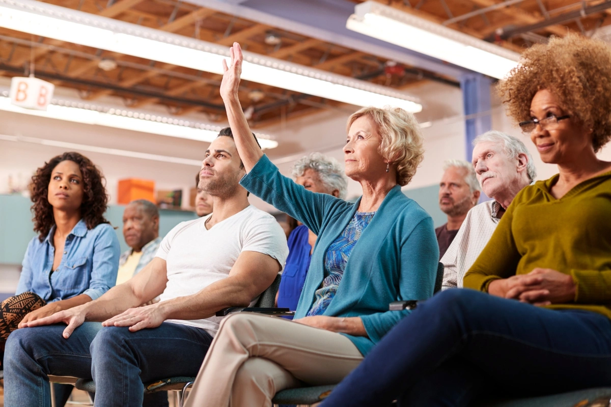 woman with raised hand asking question about Medicare PFFS plans