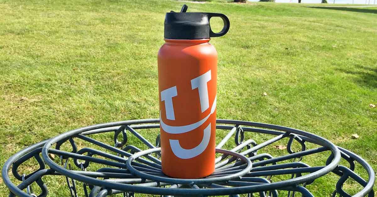 A large water bottle on top of a disc golf basket