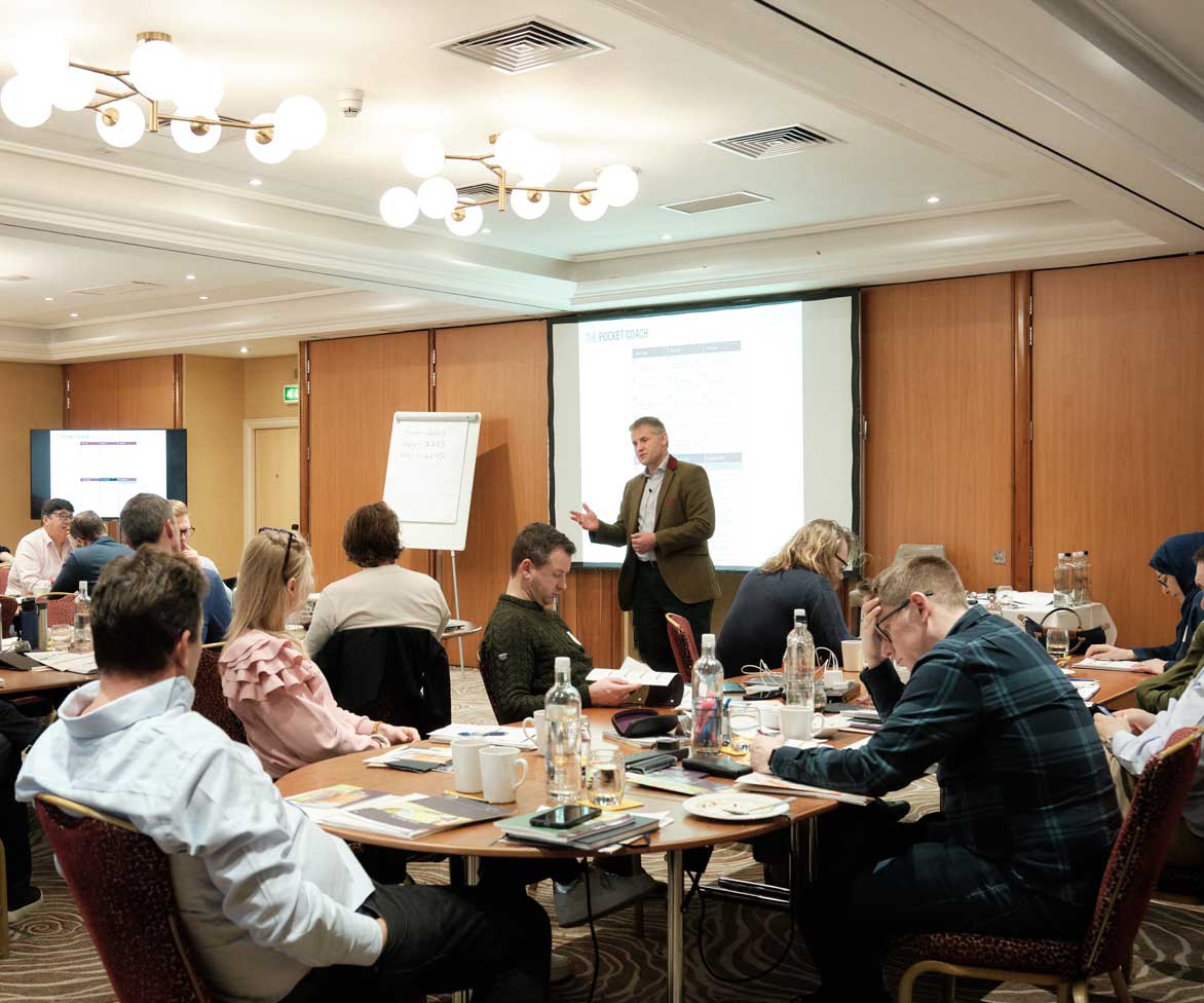 Entrepreneurs in a workshop room with a speaker at the front, coaching.