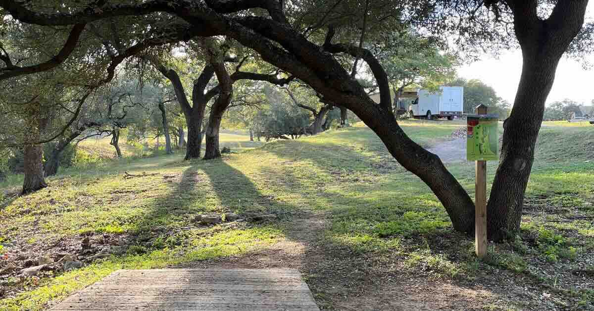 A concrete disc golf tee pad under a live oak