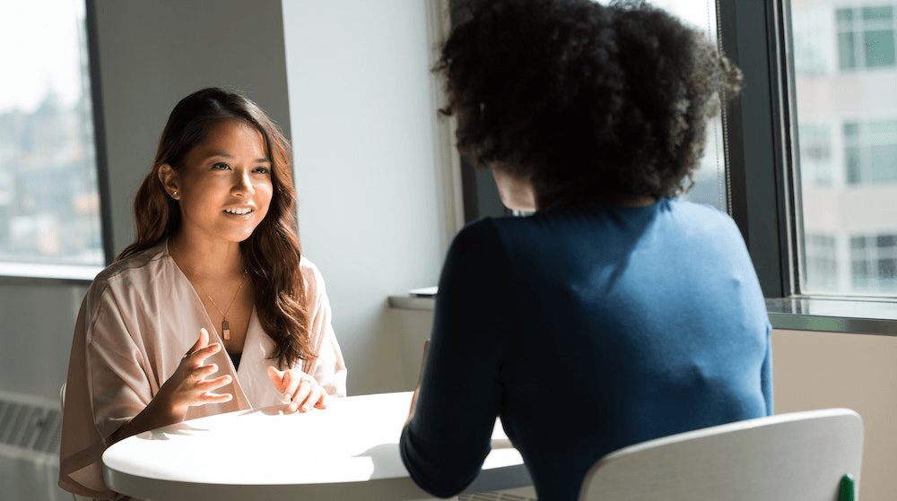 Two women talking at desk in office