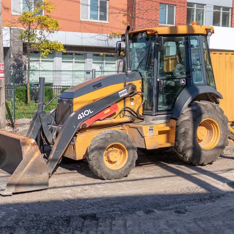 John Deere 410L backhoe with a bucket attachment on a residential project