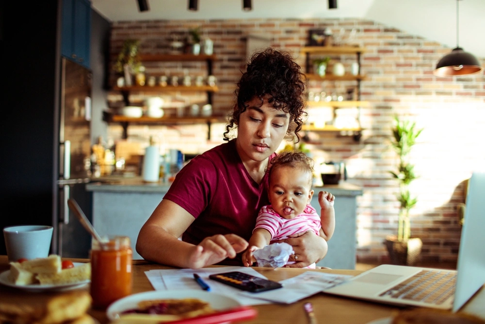 mother sat at desk with baby using a calculator