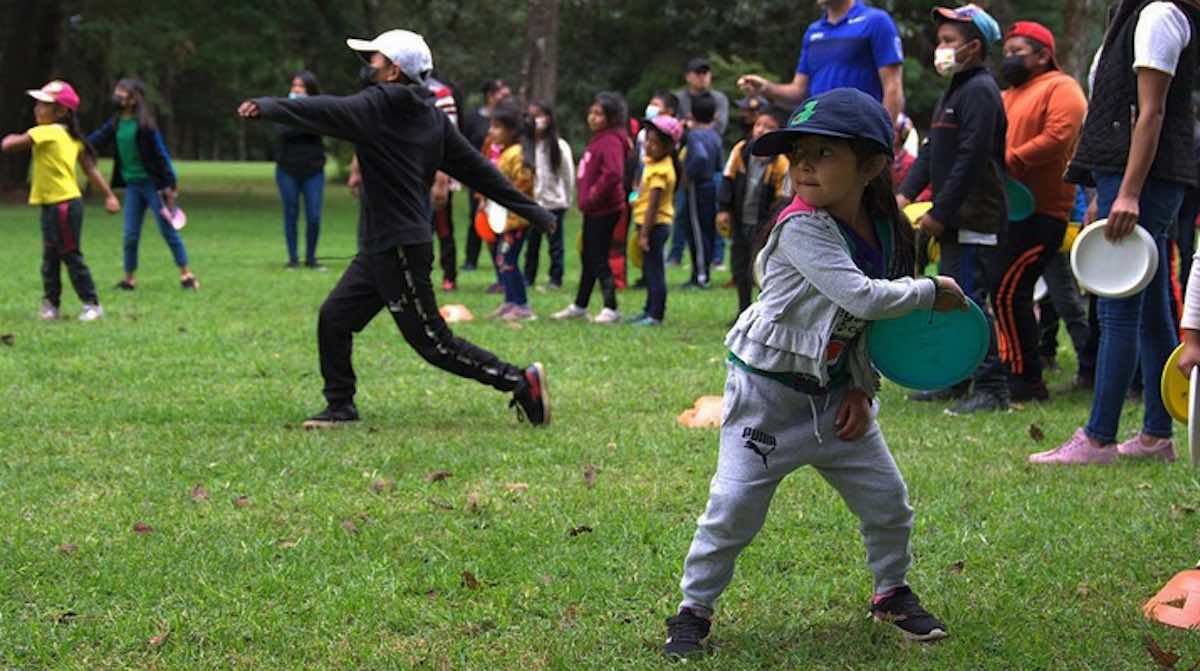 Focus on a young girl throwing a disc golf disc during a group lesson