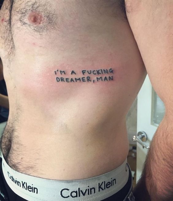 quote tattoo on man's ribs