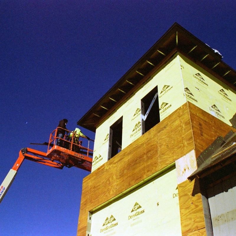 Two people on an articulating boom lift doing the sheathing