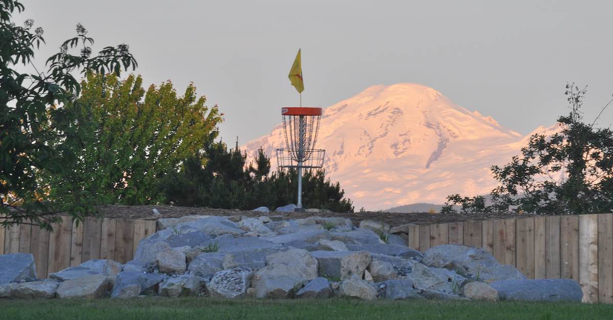 Disc golf basket ona rock mound with a snowy mountain in the background
