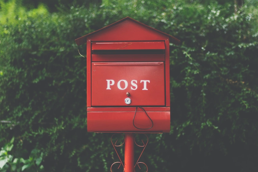 A red post box on a leafy background