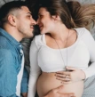 Casal hétero deitado em momento afetivo, com mulher grávida 
