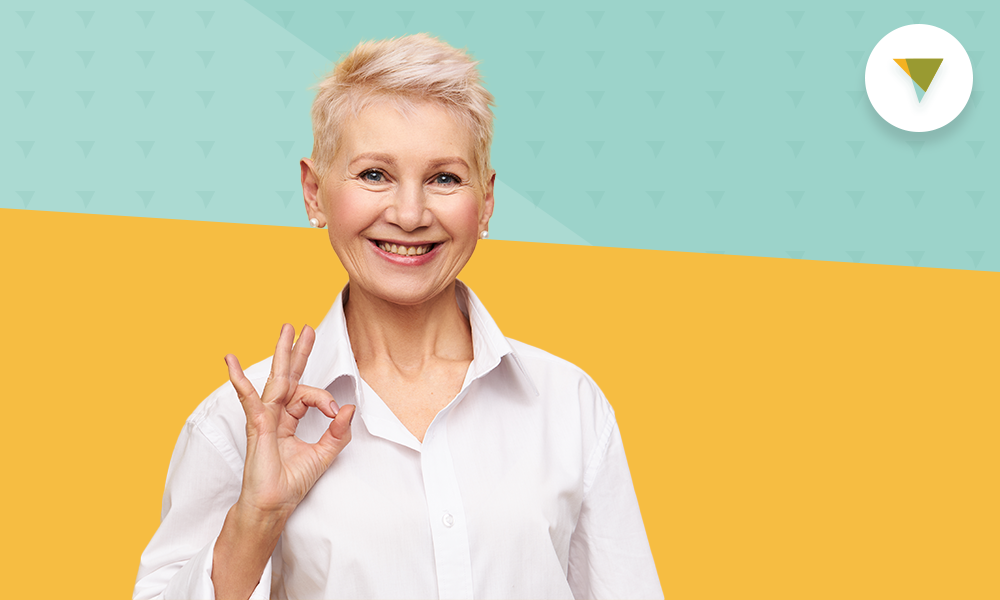 Older lady making okay symbol, looking at camera.