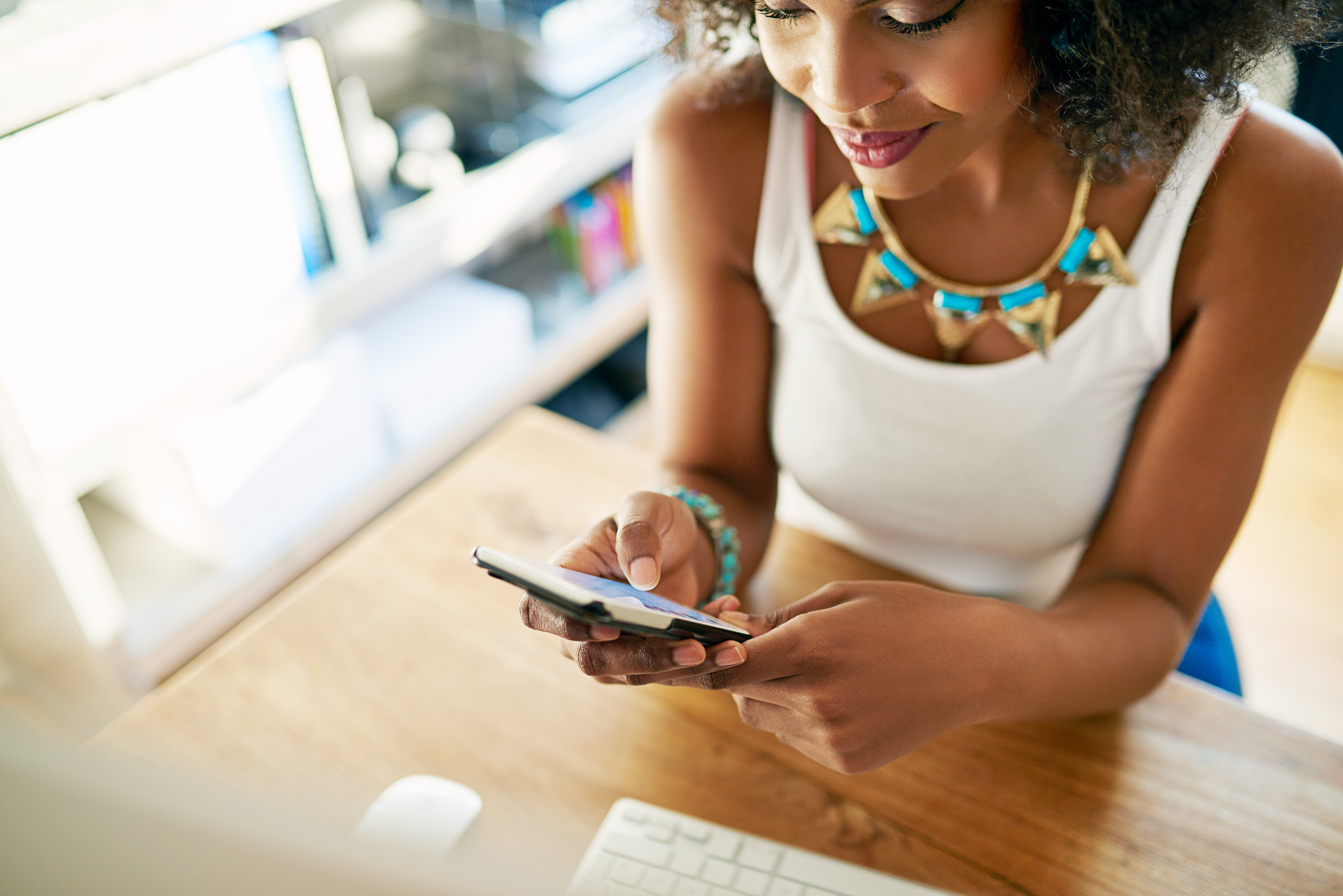 african american woman looking at her phone in an office