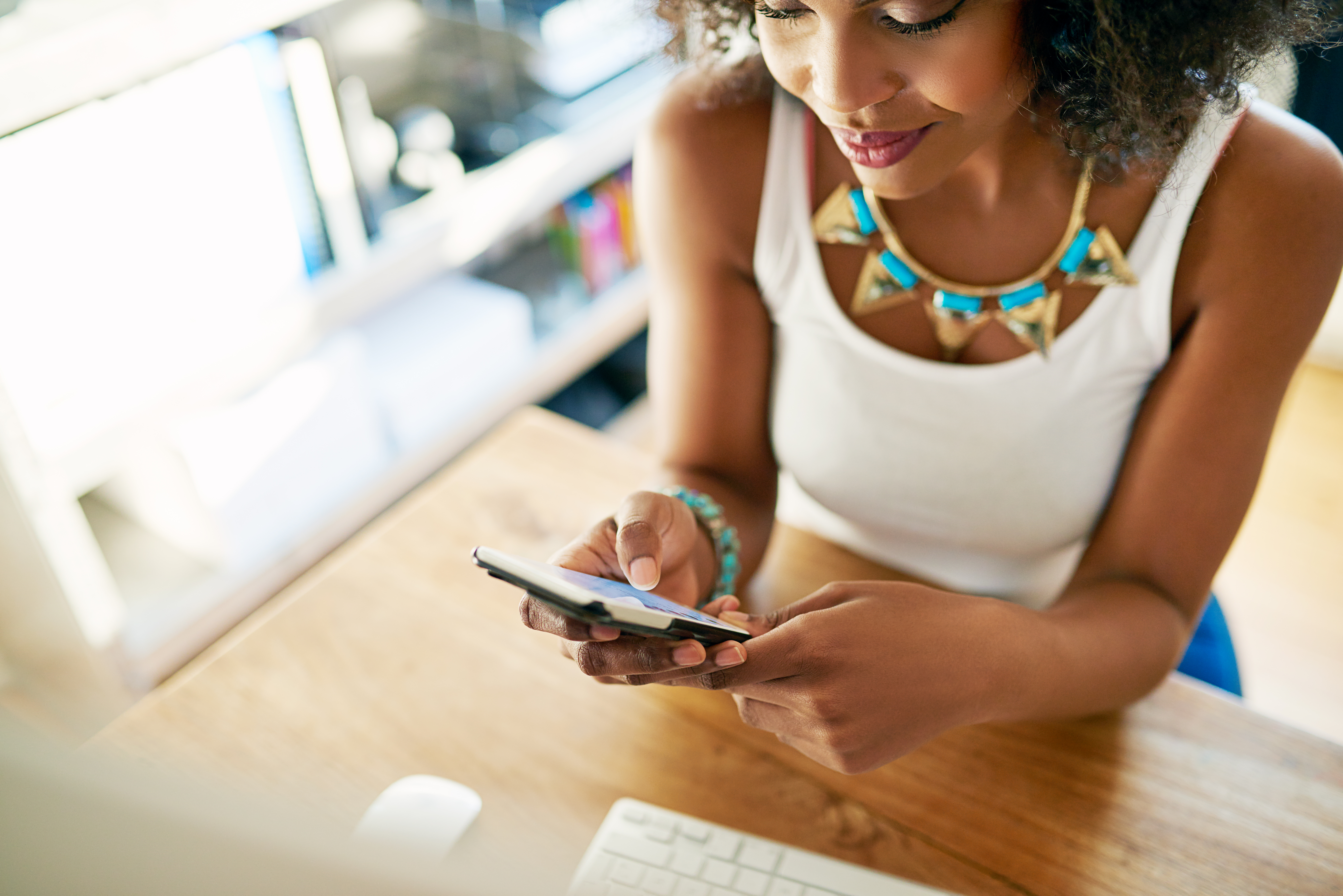 african american woman looking at her phone in an office